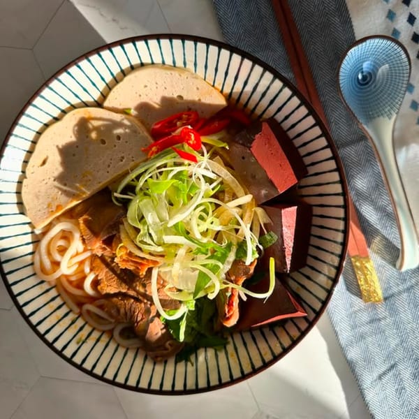 A vibrant bowl of Vietnamese Bun Bo Hue with noodles, meat, and fresh herbs.