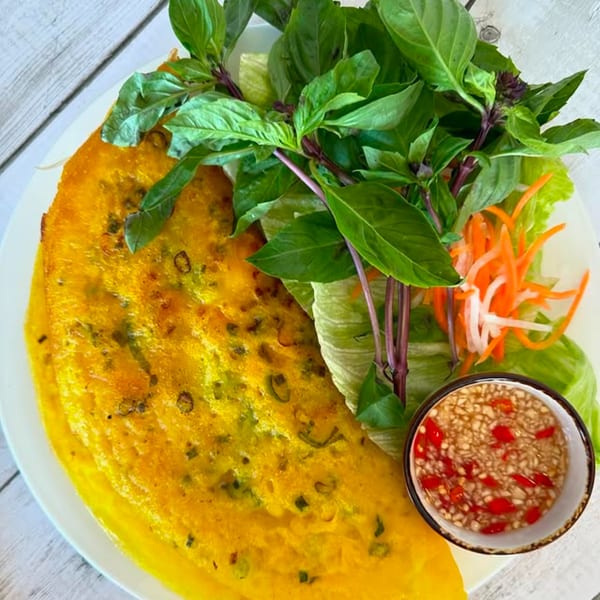 Vietnamese Banh Xeo, a savory yellow crepe, with fresh herbs, pickled vegetables, and dipping sauce.