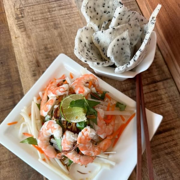 Vietnamese shrimp salad with lime, herbs, and shredded vegetables, served with dragon fruit chips.
