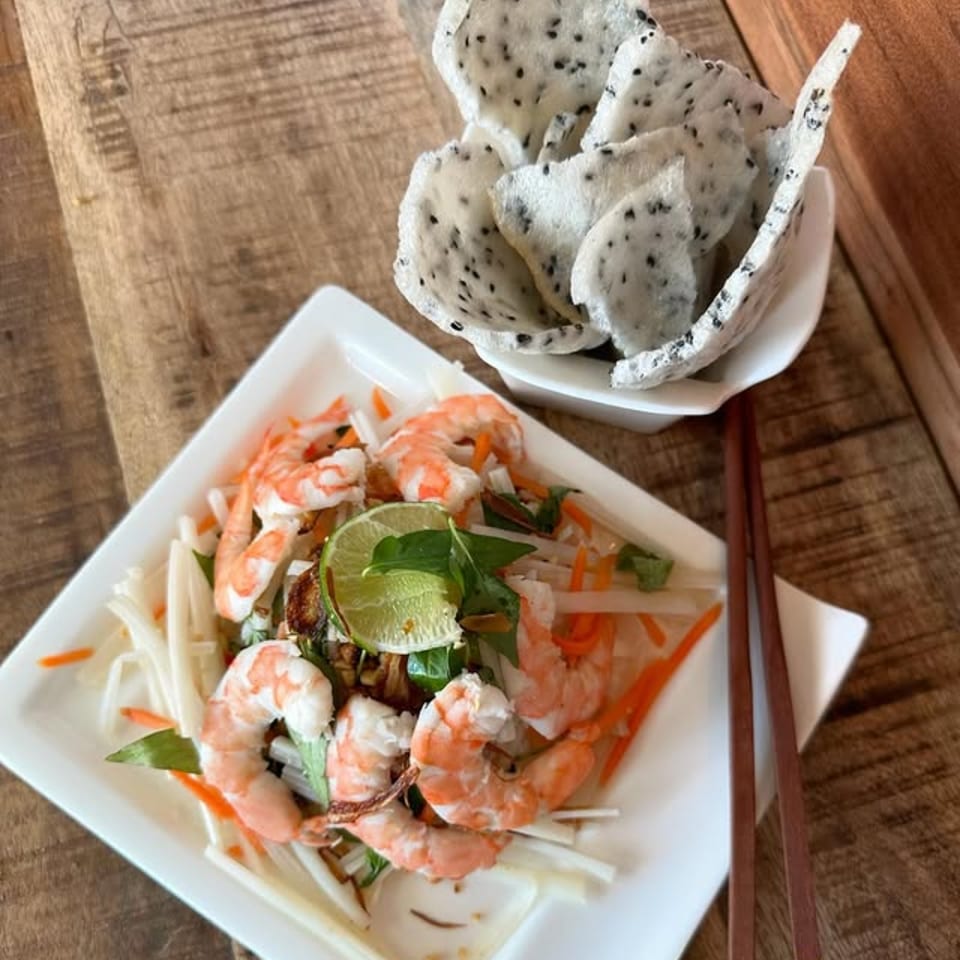 Vietnamese shrimp salad with lime, herbs, and shredded vegetables, served with dragon fruit chips.