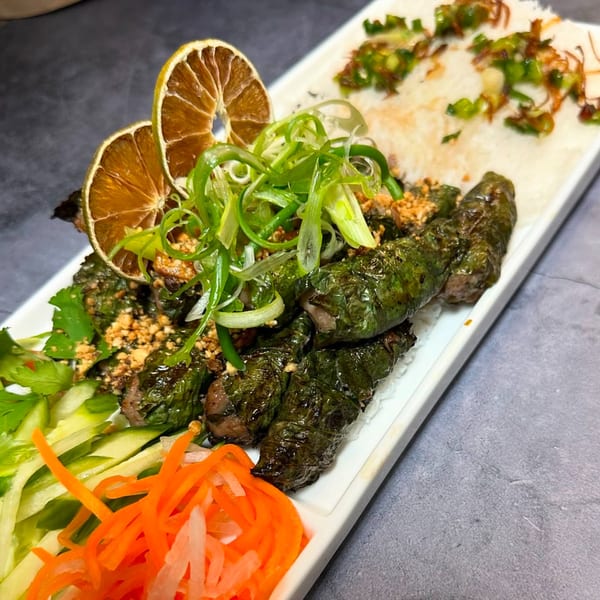 Vietnamese grilled beef in betel leaves, garnished with dried lime, scallions, peanuts, and pickled vegetables.